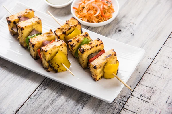 Paneer Tikka Kabab - Tandoori Indian cheese skewers, malai paneer tikka / malai paneer kabab, chilli paneer served in white plate with barbecue stick and green sauce, selective focus — Stock Photo, Image