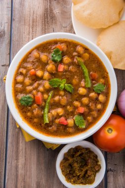 Baharatlı nohut Çola Masala veya Chana Masala veya kolesistektomi olarak da bilinen Kızarmış puri, turşu ve yeşil salata ile servis
