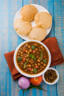 Baharatlı nohut Çola Masala veya Chana Masala veya kolesistektomi olarak da bilinen Kızarmış puri, turşu ve yeşil salata ile servis