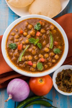 Baharatlı nohut Çola Masala veya Chana Masala veya kolesistektomi olarak da bilinen Kızarmış puri, turşu ve yeşil salata ile servis