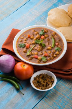 Baharatlı nohut Çola Masala veya Chana Masala veya kolesistektomi olarak da bilinen Kızarmış puri, turşu ve yeşil salata ile servis