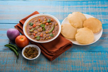 Baharatlı nohut Çola Masala veya Chana Masala veya kolesistektomi olarak da bilinen Kızarmış puri, turşu ve yeşil salata ile servis