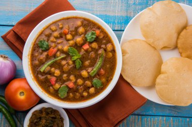 Baharatlı nohut Çola Masala veya Chana Masala veya kolesistektomi olarak da bilinen Kızarmış puri, turşu ve yeşil salata ile servis