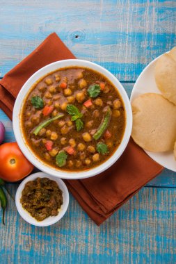 Baharatlı nohut Çola Masala veya Chana Masala veya kolesistektomi olarak da bilinen Kızarmış puri, turşu ve yeşil salata ile servis