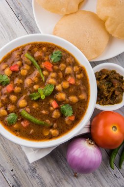 Baharatlı nohut Çola Masala veya Chana Masala veya kolesistektomi olarak da bilinen Kızarmış puri, turşu ve yeşil salata ile servis