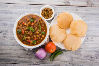 Baharatlı nohut Çola Masala veya Chana Masala veya kolesistektomi olarak da bilinen Kızarmış puri, turşu ve yeşil salata ile servis