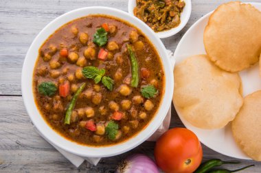 Baharatlı nohut Çola Masala veya Chana Masala veya kolesistektomi olarak da bilinen Kızarmış puri, turşu ve yeşil salata ile servis