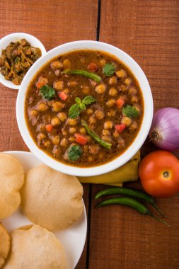 Baharatlı nohut Çola Masala veya Chana Masala veya kolesistektomi olarak da bilinen Kızarmış puri, turşu ve yeşil salata ile servis