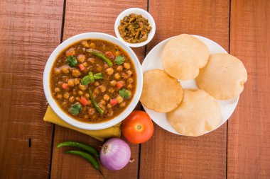 Baharatlı nohut Çola Masala veya Chana Masala veya kolesistektomi olarak da bilinen Kızarmış puri, turşu ve yeşil salata ile servis