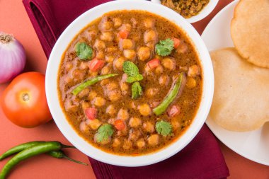 Baharatlı nohut Çola Masala veya Chana Masala veya kolesistektomi olarak da bilinen Kızarmış puri, turşu ve yeşil salata ile servis