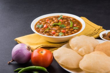 Baharatlı nohut Çola Masala veya Chana Masala veya kolesistektomi olarak da bilinen Kızarmış puri, turşu ve yeşil salata ile servis