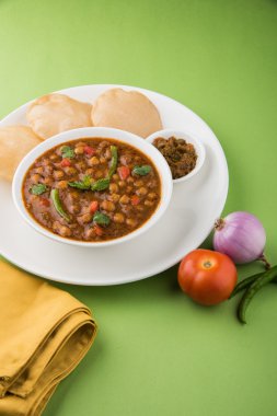 Baharatlı nohut Çola Masala veya Chana Masala veya kolesistektomi olarak da bilinen Kızarmış puri, turşu ve yeşil salata ile servis