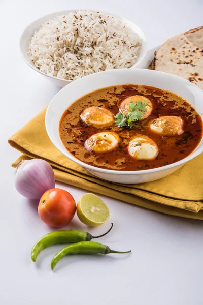 egg curry with roti/chapati and jeera rice, tasty and spicy anda curry with roti and rice, indian egg masala curry served in ceramic bowl with roti, salad and jeera rice