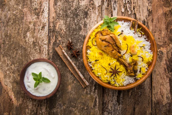 Chicken Biryani with yogurt dip on beautiful moody background, selective focus