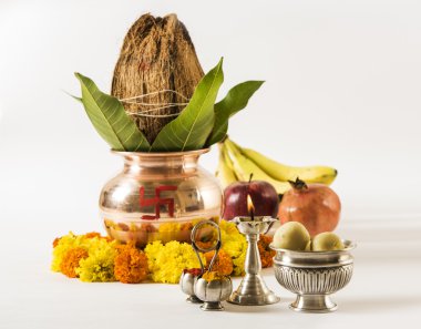 hindu puja elements, kalash with coconut and mango leaves,diya, haldi kumkum and indian sweet pedha in silver bowl isolated on red background clipart