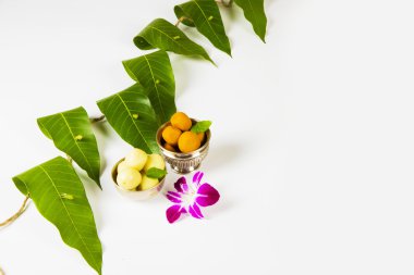 hint tatlı pedha ve orkide çiçek ile mango yaprakları çelenk . Hindu dininde uğurludur ve Hindistan'daki festivallerde süs olarak kullanılır..