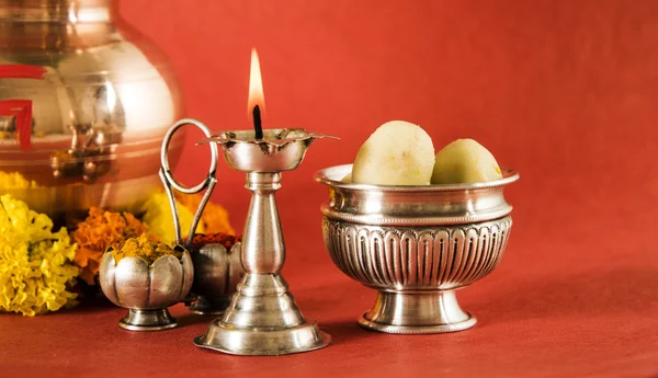 Hindu puja elements, kalash with coconut and mango leaves,diya, haldi kumkum and indian sweet pedha in silver bowl isolated on red background — Stock Photo, Image
