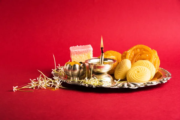 Bellamente decorado Pooja Thali para la celebración o adoración diwali, que tiene dulces indios, lámpara de plata, flores, huldi o cúrcuma en polvo y kumkum en un plato decorado con plata — Foto de Stock