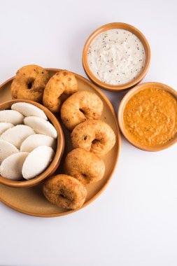 Sambar ile Sambar Vada & Idli, hindistan cevizi chutney ve kırmızı domates chutney, Hint Çanak toprak plaka ve beyaz arka plan üzerinde kase servis, ön görünüm, beyaz arka plan üzerinde izole