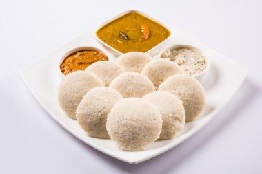 beyaz arka plan üzerinde beyaz seramik kare plaka ve kase geleneksel güney hint gıda, idli veya idly sambar ve beyaz hindistan cevizi chutney ve kırmızı chutney ile, ön görünümü beyaz arka plan üzerinde izole