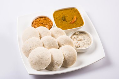 Sambar Vada & Idli sambar, hindistan cevizi chutney ve kırmızı domates chutney ile, Hint Çanak beyaz plaka ve beyaz arka plan üzerinde kase servis