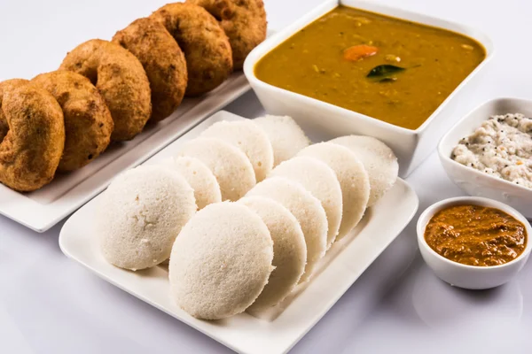 Sambar Vada & Idli con sambar, chutney di cocco e chutney di pomodoro rosso, piatto indiano servito in piatto bianco e ciotola su sfondo bianco — Foto Stock