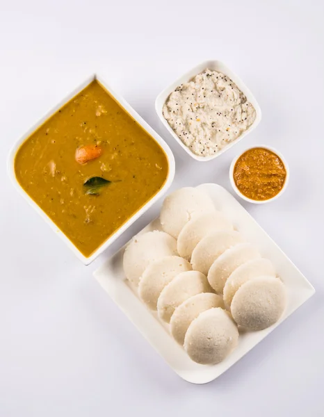 traditional south indian food, idli or idly with sambar and white coconut chutney and red chutney in white ceramic square plate and bowl on white background, front view isolated on white background
