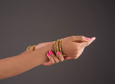 elinde altın bilezik, altın bilezik giyen kız el zarif pozlar, tasarımcı altın bilezik ve el, altın bilezik ile kız elleri, closeup, gri arka plan üzerinde izole