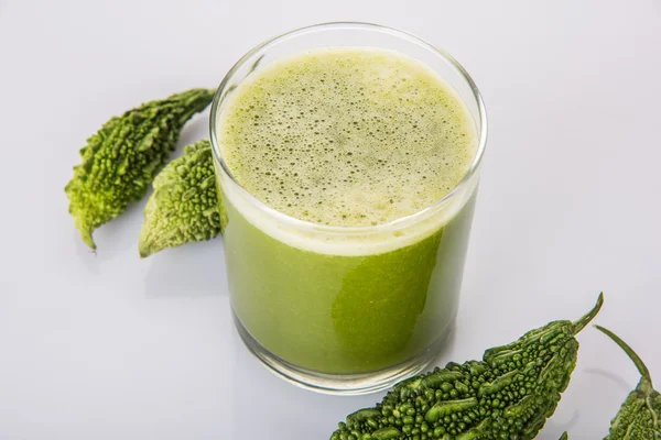 Herbal juice of green momodica in a glass with sliced vegetables, karela juice or bitter gourd juice