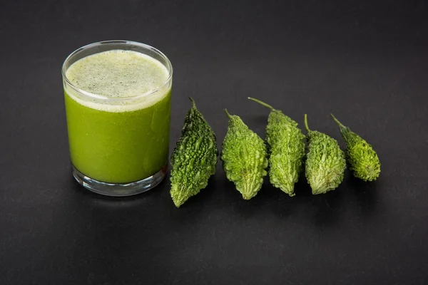 Herbal juice of green momodica in a glass with sliced vegetables, karela juice or bitter gourd juice