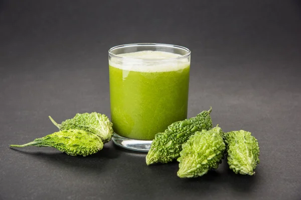 Herbal juice of green momodica in a glass with sliced vegetables, karela juice or bitter gourd juice