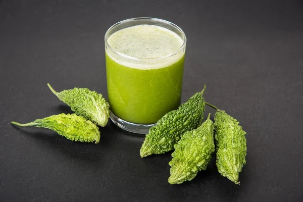 Herbal juice of green momodica in a glass with sliced vegetables, karela juice or bitter gourd juice