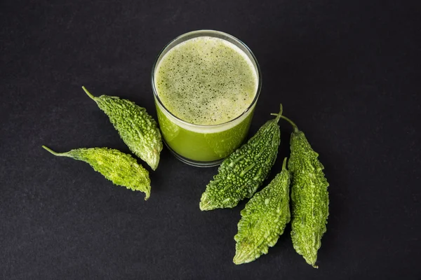 Herbal juice of green momodica in a glass with sliced vegetables, karela juice or bitter gourd juice