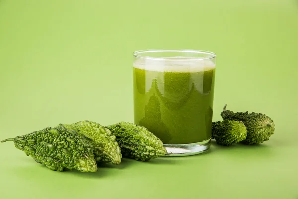 Herbal juice of green momodica in a glass with sliced vegetables, karela juice or bitter gourd juice