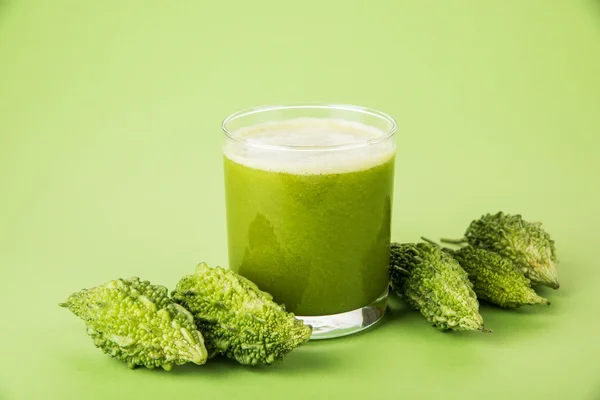 Herbal juice of green momodica in a glass with sliced vegetables, karela juice or bitter gourd juice