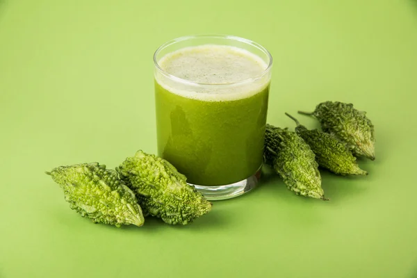 Herbal juice of green momodica in a glass with sliced vegetables, karela juice or bitter gourd juice