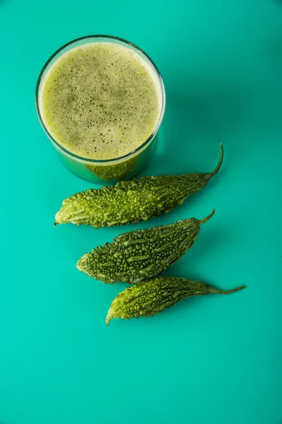 Herbal juice of green momodica in a glass with sliced vegetables, karela juice or bitter gourd juice