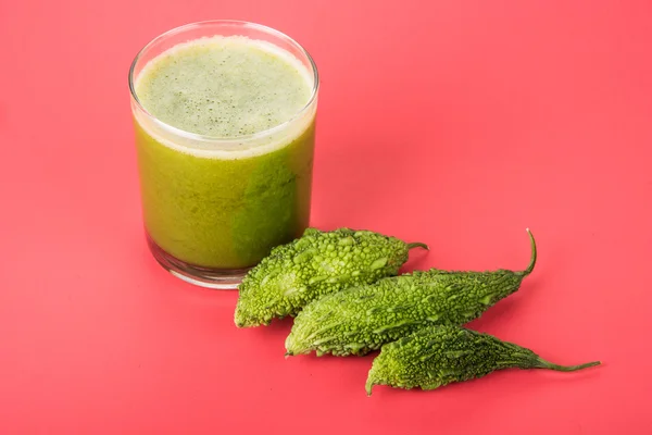 Herbal juice of green momodica in a glass with sliced vegetables, karela juice or bitter gourd juice