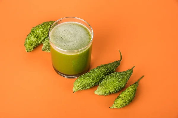 Herbal juice of green momodica in a glass with sliced vegetables, karela juice or bitter gourd juice