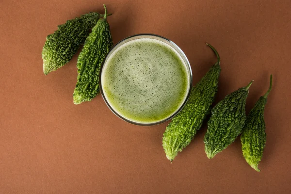 Herbal juice of green momodica in a glass with sliced vegetables, karela juice or bitter gourd juice