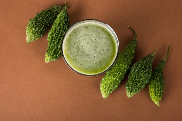 Herbal juice of green momodica in a glass with sliced vegetables, karela juice or bitter gourd juice