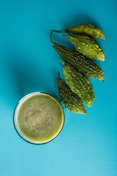 Herbal juice of green momodica in a glass with sliced vegetables, karela juice or bitter gourd juice