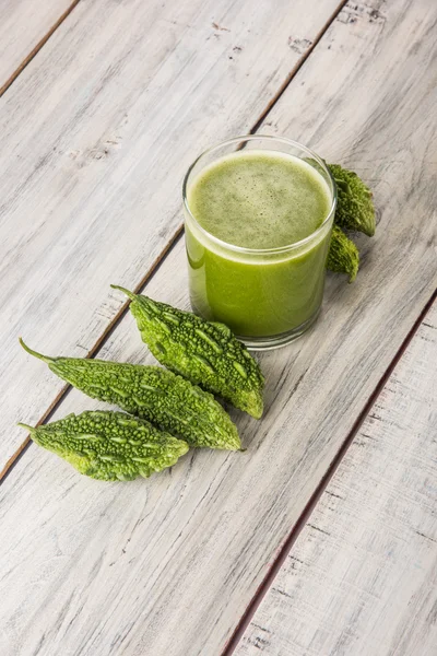 Herbal juice of green momodica in a glass with sliced vegetables, karela juice or bitter gourd juice