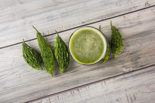 Herbal juice of green momodica in a glass with sliced vegetables, karela juice or bitter gourd juice