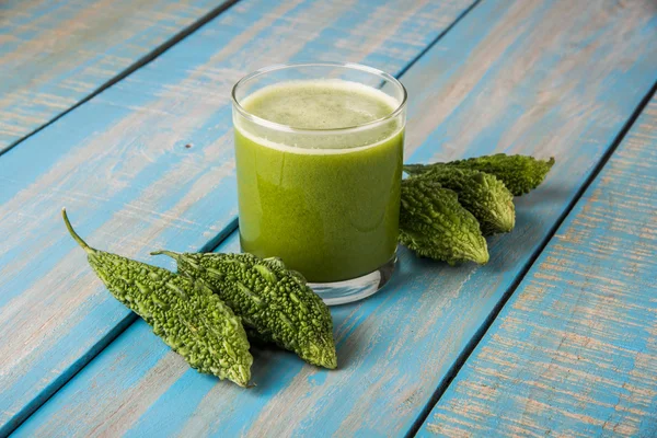 Herbal juice of green momodica in a glass with sliced vegetables, karela juice or bitter gourd juice