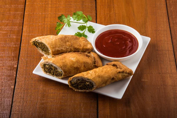 Sprint rolls or kothimbir vadi or sambar vadi or coriander spring rolls, indian snacks, tastes great with tea and tomato ketchup or tomato sauce, in square white plate over colourful background — Stock Photo, Image