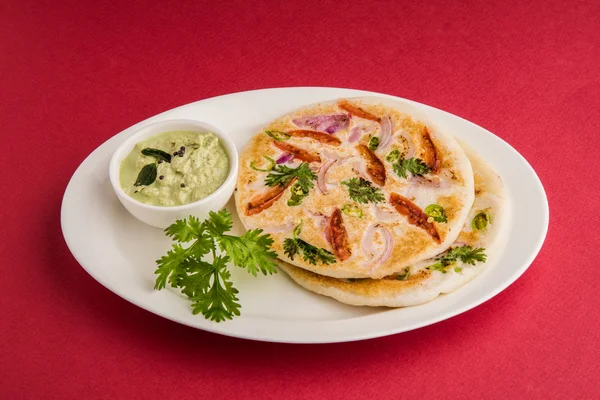 Comida india del sur, dos uttapam con chutney de coco en placa de cerámica blanca con hoja de cilantro, primer plano y vista frontal, aislado sobre fondo blanco — Foto de Stock