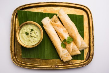Hindistan cevizi yaprağı üzerinde pirinç tepsihindistan cevizi chutney ile 3 dosa rulo, favori güney hint yemek, üst görünümü, beyaz arka plan üzerinde izole