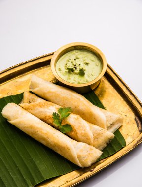 Hindistan cevizi yaprağı üzerinde pirinç tepsihindistan cevizi chutney ile 3 dosa rulo, favori güney hint yemek, üst görünümü, beyaz arka plan üzerinde izole