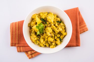 patates kuru ve baharatlı reciepy da aalu sabji veya aalu bhaji olarak bilinen, roti / chapati / paratha / dosa / naan ile servis, beyaz plaka kahverengi rustik kase servis, sarı arka plan üzerinde izole